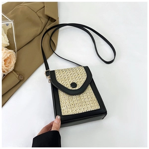 Detail of woven straw crossbody bag featuring black leather trim and round button closure