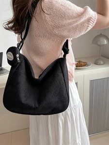 Minimalist black corduroy hobo bag with matching coin purse shown on female model