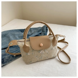 Détail du sac bandoulière tissé à la main avec broderies florales délicates roses et blanches