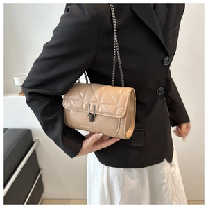 Détail d'un petit sac beige matelassé avec bandoulière chaîne et fermoir métallique