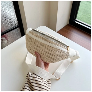 Détail de la texture paille tissée et bordure en cuir blanc du sac banane d'été