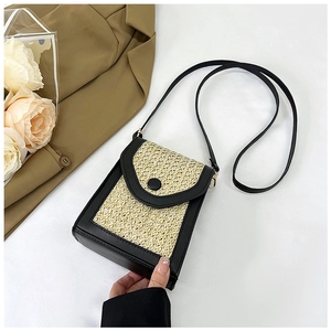 Close-up of beige straw woven crossbody bag with black leather trim and decorative buckle