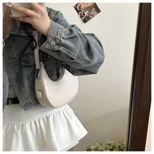 Mirror selfie showing a white crescent shoulder bag in smooth PU leather with a blue denim jacket