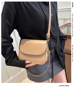 Beige Umhängetasche aus PU-Leder mit verstellbarem Riemen und Logo an einem Modell