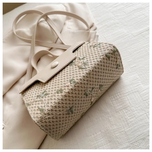 Detailed macro view of woven handbag with green leaves and delicate floral embroidery