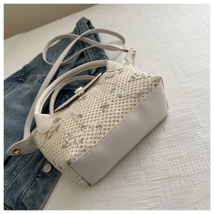 Détail du sac à main tissé avec broderies florales et lanières en cuir blanc