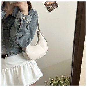 Close-up of sleek cream white crescent underarm bag with silver metallic hardware