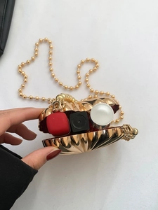 Golden shell-shaped mini clutch with pearl chain, featuring a polished metallic texture