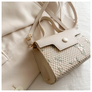 Detail of floral embroidered woven texture and smooth faux leather on ivory handbag