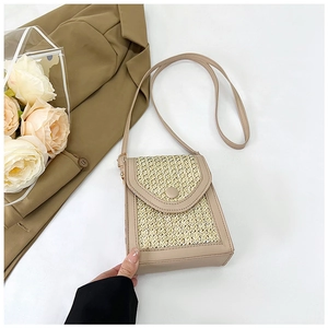 Macro detail of straw woven crossbody bag with leather edges and snap button closure