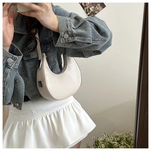 Detail of minimalist beige crescent bag featuring smooth leather and silver hardware accents