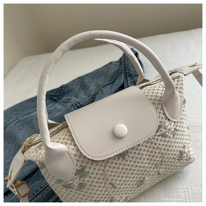 Détail d'un sac à main tissé avec broderie florale et poignée en cuir blanc