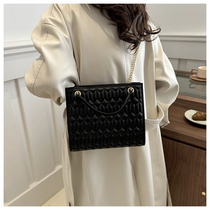 Close-up of black quilted shoulder bag with gold chain strap and detailed PU leather texture