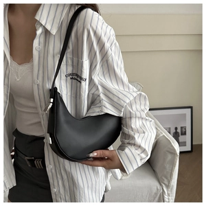 Detail of minimalist black crescent bag with smooth leather finish and silver buckle strap