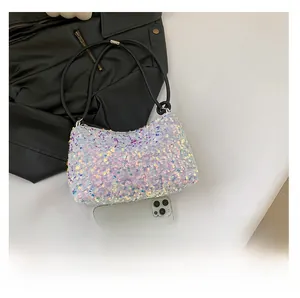Detail view of mini holographic sequin shoulder bag next to a phone for size comparison