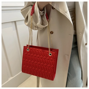 Close-up of red quilted chain bag showing geometric texture and gold metal hardware