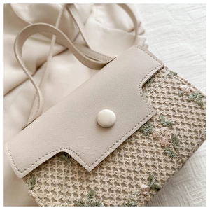 Detail of cream woven bag with floral embroidery and lychee pattern leather flap
