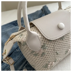 Vue détaillée du sac tissé crème avec broderies florales délicates et poignée en cuir