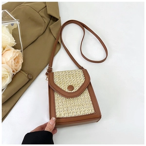 Detailed view of straw crossbody bag showing ivory woven texture and brown leather trim