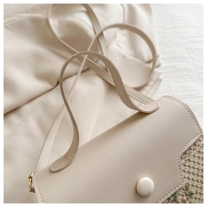 Detail of lychee textured leather and embroidered woven fabric on beige handbag