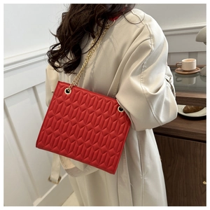 Detail view of the vibrant red quilted geometric shoulder bag with golden chain strap
