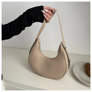 Close-up of beige crescent underarm bag with smooth matte finish and silver hardware