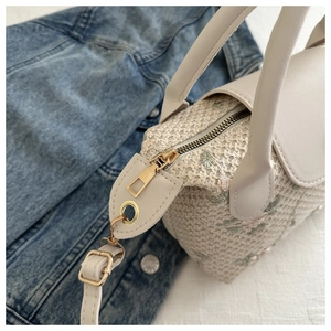 Détail d'un sac à main tissé beige avec broderie florale et finitions dorées
