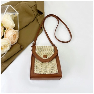 Detail of straw woven crossbody bag with brown leather trim and button closure