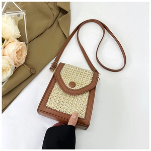 Detail of a woven straw and brown leather crossbody phone bag with snap button closure