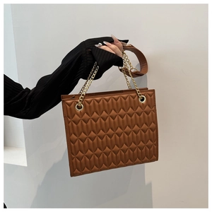 Detail of coffee brown quilted tote bag with gold chain strap and leather shoulder strap