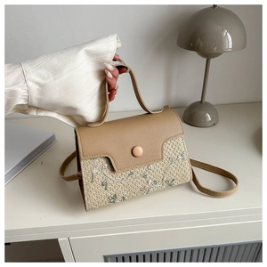 Detail of light khaki woven handbag featuring floral embroidery and round magnetic buckle