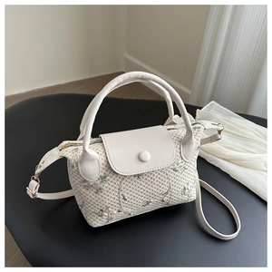 Détail du sac à main tissé crème avec broderie florale délicate rose et vert tendre