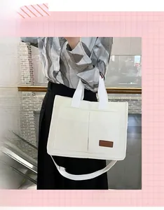 Close-up of white corduroy tote bag detail with dual pockets and brown fashion label