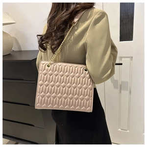 Detail of beige quilted shoulder bag with gold chain strap on olive blazer outfit
