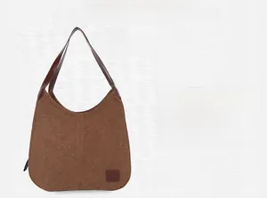 Détail d'un sac hobo en toile marron avec poignée en cuir vintage et écusson décoratif