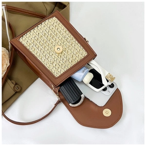 Detail view showing internal storage for phone and sunglasses in straw woven bag