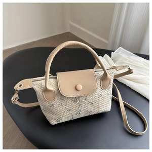 Détail de broderie florale sur un sac à bandoulière tissé avec poignées en cuir