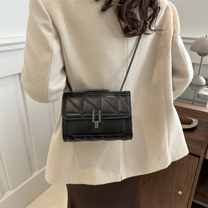 Sac bandoulière matelassé noir chic avec chaîne en métal porté par un mannequin