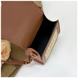 Close-up of brown straw woven mini crossbody bag with gold hardware and black lining