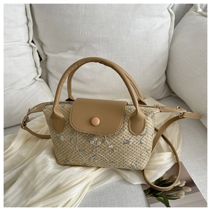 Détail du sac à main en paille tressée avec broderie florale et finitions en cuir