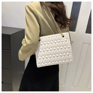 Close-up of white quilted crossbody bag with gold chain strap and diamond texture