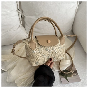 Détail du sac à main en paille beige avec broderie de feuilles vertes sur soie crème