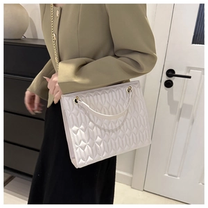 Close-up of white leaf quilted pattern on handbag with elegant gold chain strap details