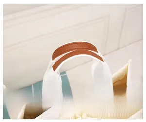 Detail of reinforced brown leather handle on a white corduroy tote bag for comfort