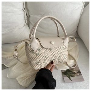 Gros plan d'un mini sac tressé main avec broderies florales et poignée en PU
