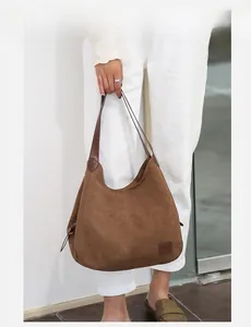 Sac hobo en daim marron avec bandoulière en cuir porté par un mannequin en tenue décontractée