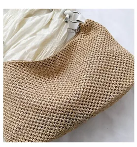 Close-up of woven straw shoulder bag with metallic zipper and white strap detail