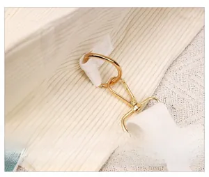 Detailed close-up of golden metal lobster clasp and ring on beige corduroy handbag