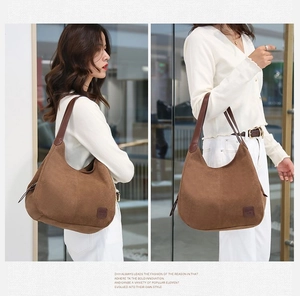 Détail d'un grand sac cabas marron en toile avec lanières en cuir et logo latéral
