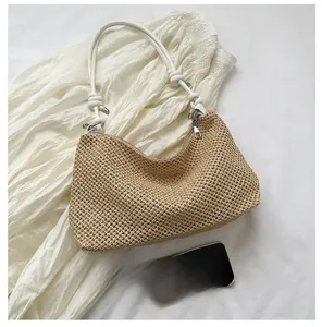 Detail of straw shoulder bag with thick cotton rope handles and crescent shape design